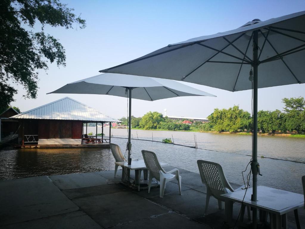 un tavolo e sedie con ombrelloni accanto a un fiume di River Marina Resort a Uthai Thani