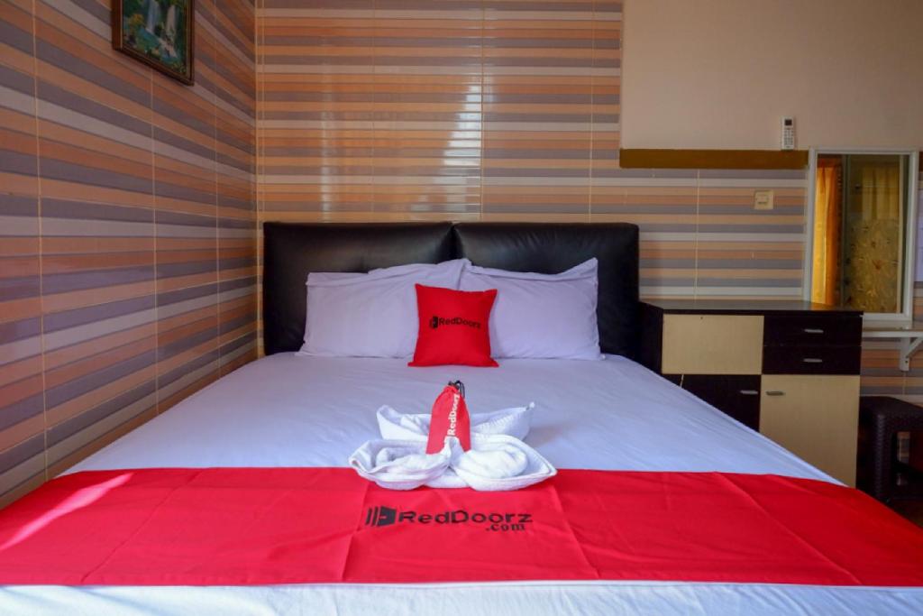 Una cama con toallas rojas y blancas. en RedDoorz near Kendari Beach 2, en Kendari