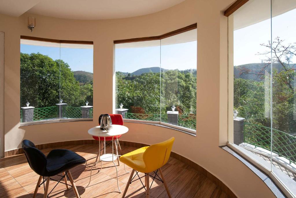 Zimmer mit einem Tisch, Stühlen und großen Fenstern in der Unterkunft 3BR Cocoon Valley Hideout - Nature's Lap in Vagamon