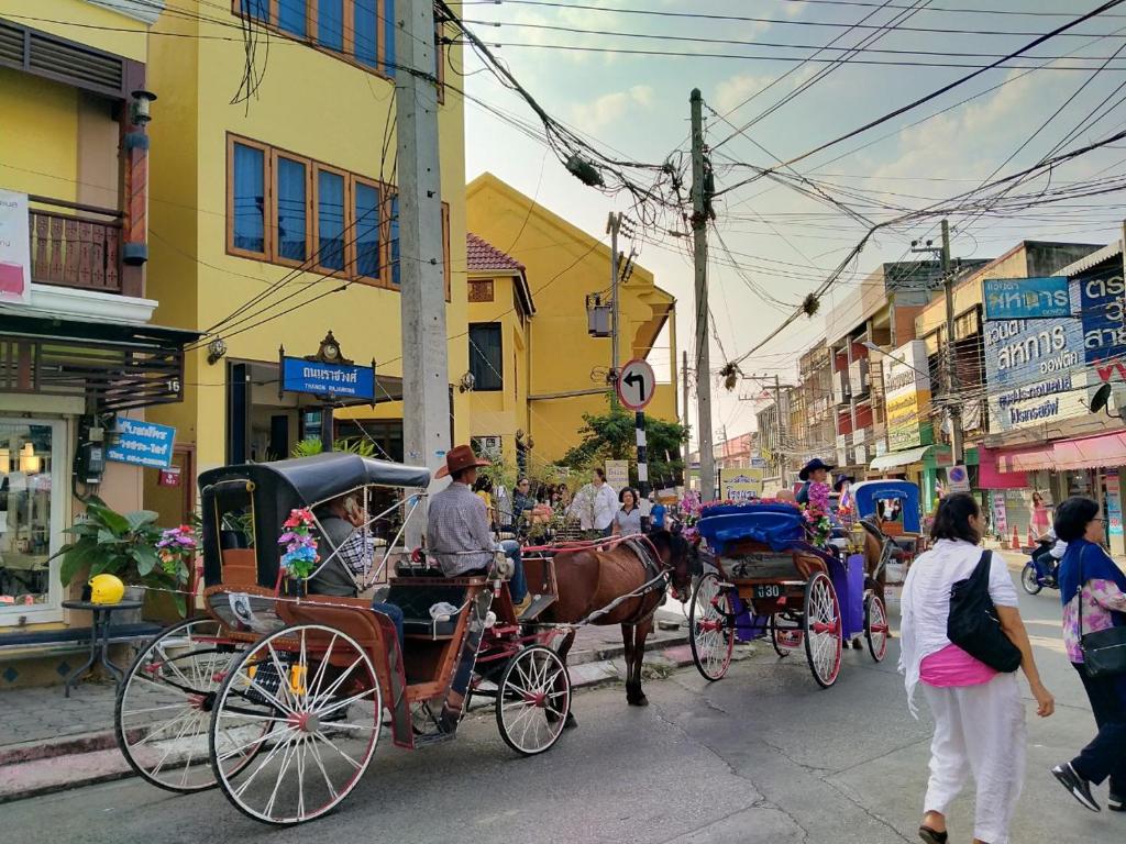 a horse drawn carriage on a city street with people at Ban Mae Boonthong in Lampang