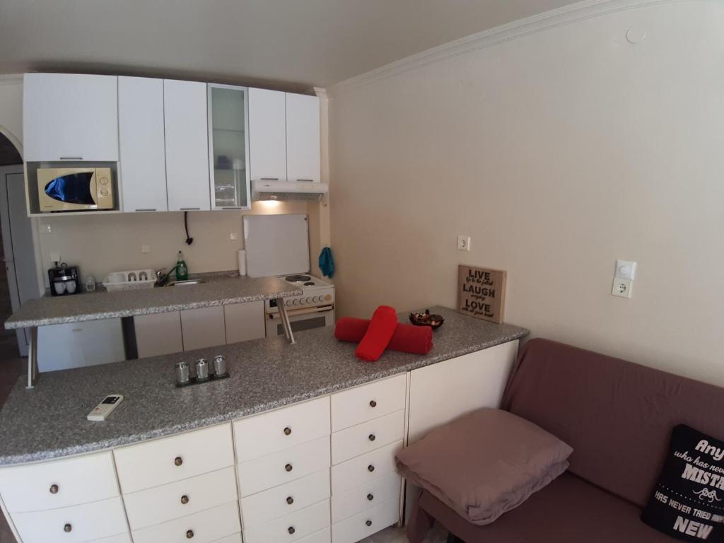 a kitchen with white cabinets and red pillows on the counter at Studio at Thessaloniki in Thessaloniki