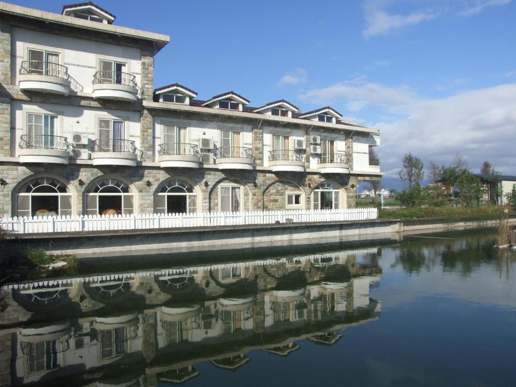 - un grand bâtiment à côté d'une étendue d'eau dans l'établissement Aurora, à Wujie