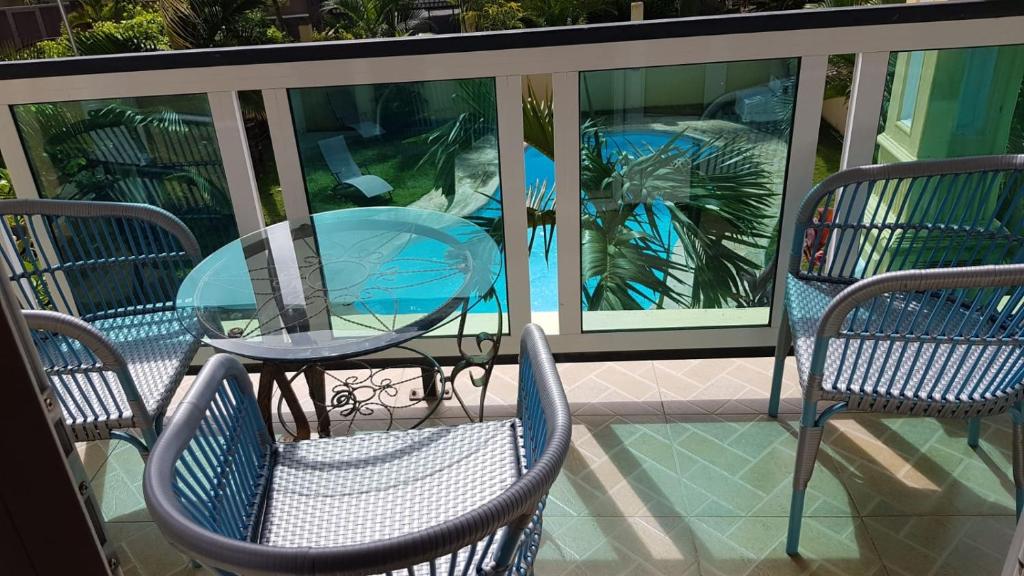 a glass table and chairs on a balcony at Apartment Derningham in Trou aux Biches