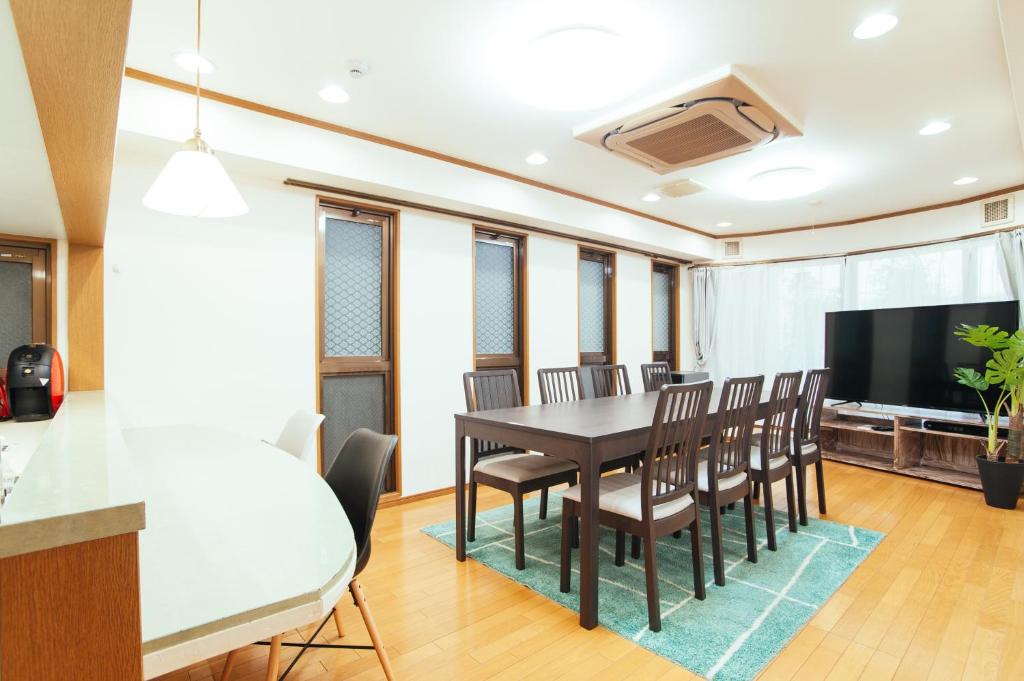 una sala da pranzo con tavolo, sedie e TV a schermo piatto di まるまる貸切,羽田空港から一番近いyu`s house a Tokyo