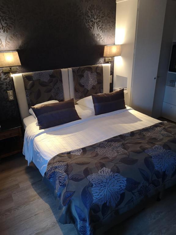 a large bed in a bedroom with two lamps at Villa Augeval Hôtel de charme & Spa in Deauville