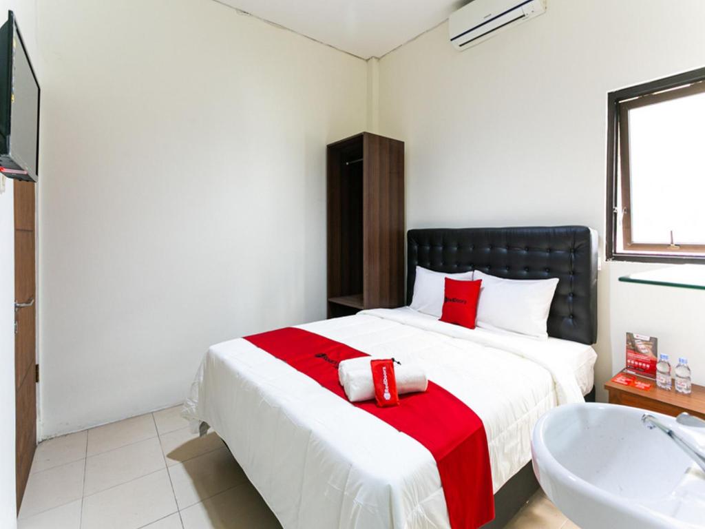 a bedroom with a bed and a tub and a sink at RedDoorz @ Urip Sumoharjo Solo in Solo