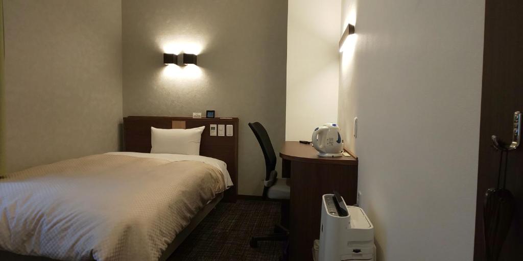 um quarto com uma cama e uma secretária com um telefone em Ueno First City Hotel em Tóquio