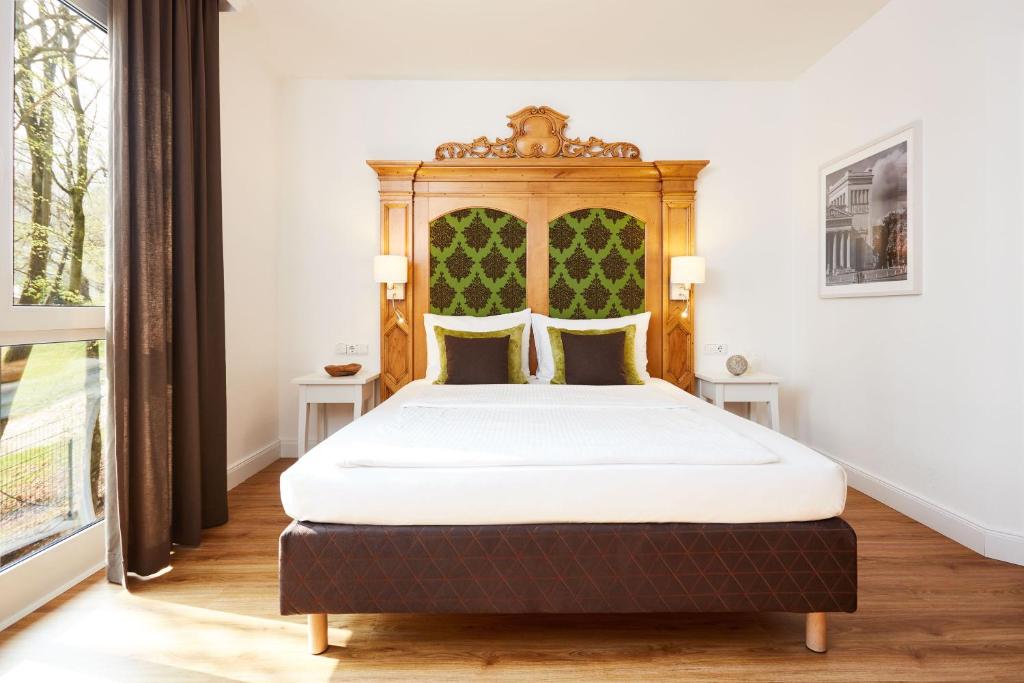 a bed with a wooden headboard in a room at Hotel Prinzregent München Messe in Munich