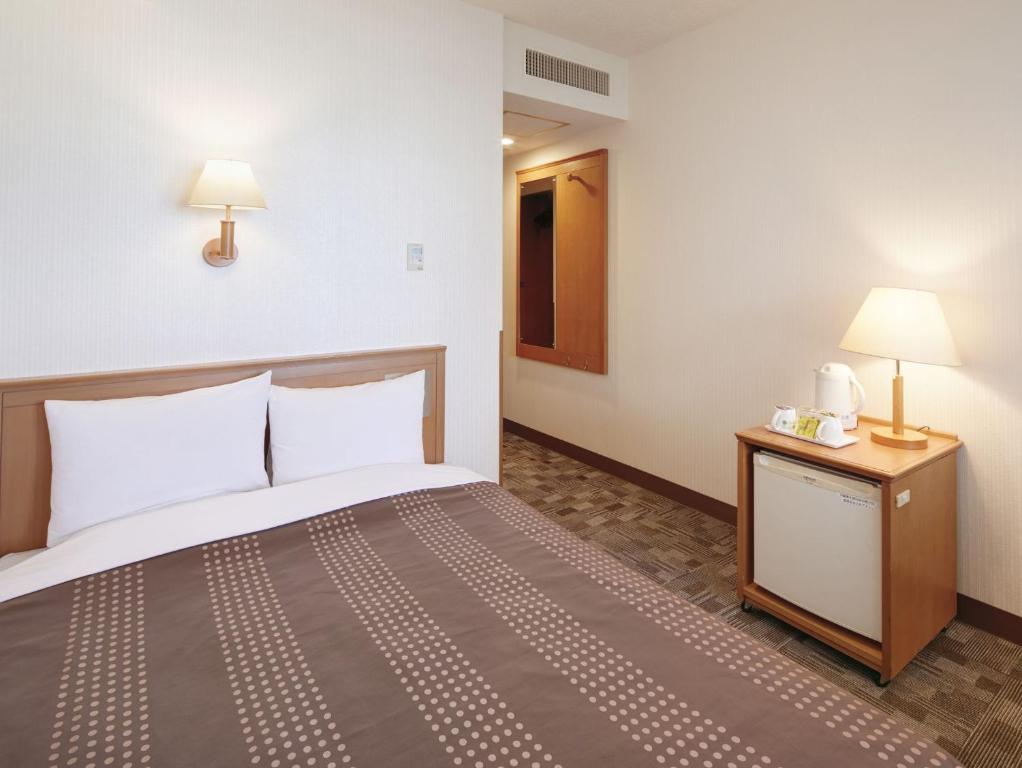 a hotel room with a bed and a night stand at Hotel Roco Inn Okinawa in Naha