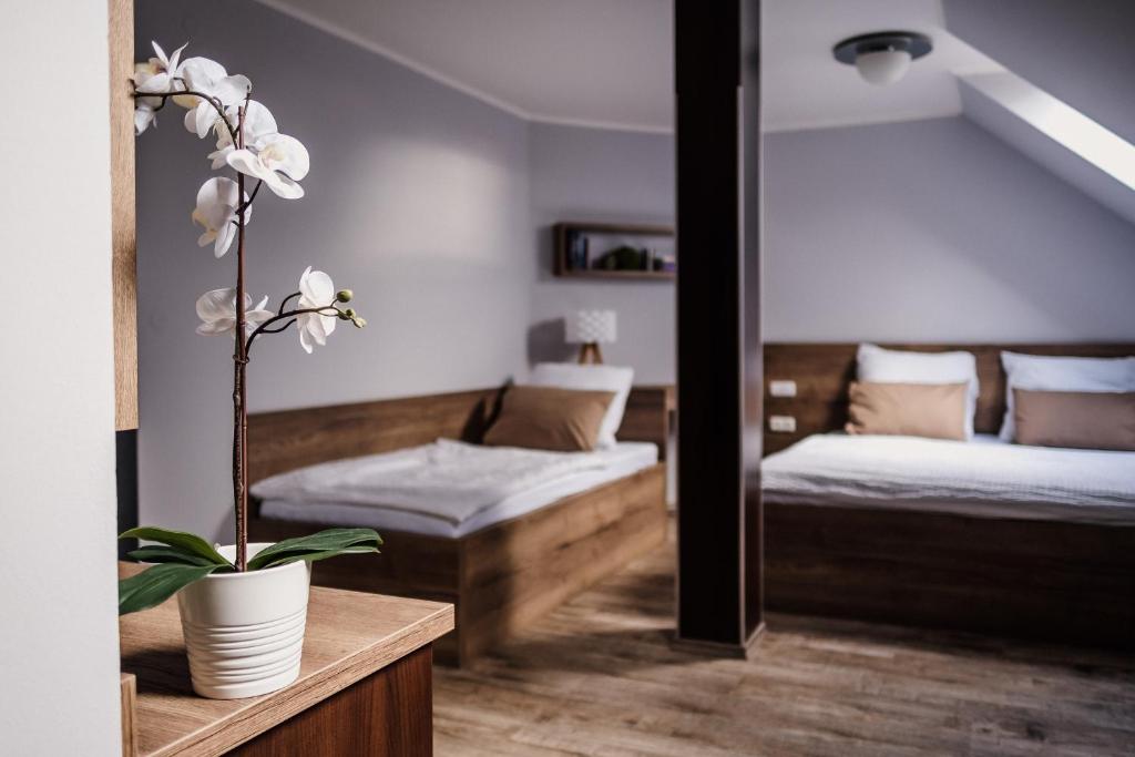 a bedroom with two beds and a plant on a table at Penzion Prestige Tennis Park in Frýdek-Místek