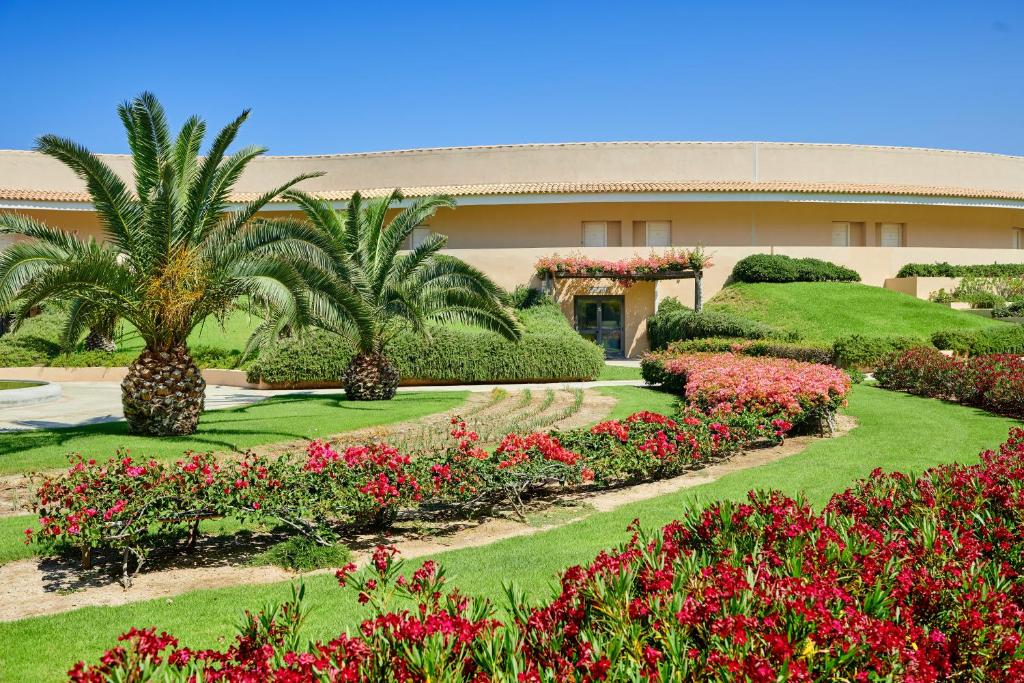 a building with a garden with flowers and palm trees at Capovaticano Resort Thalasso Spa in Capo Vaticano