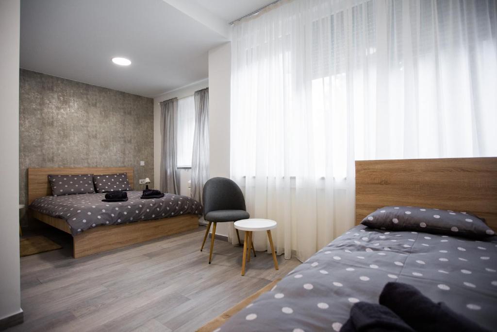 a bedroom with two beds and a table and a chair at Gloria Rooms in Požega