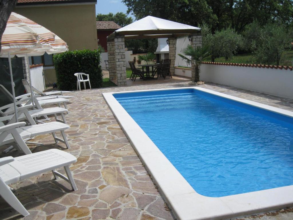 a swimming pool with chairs and an umbrella at Apartments Villa Ksenija in Umag