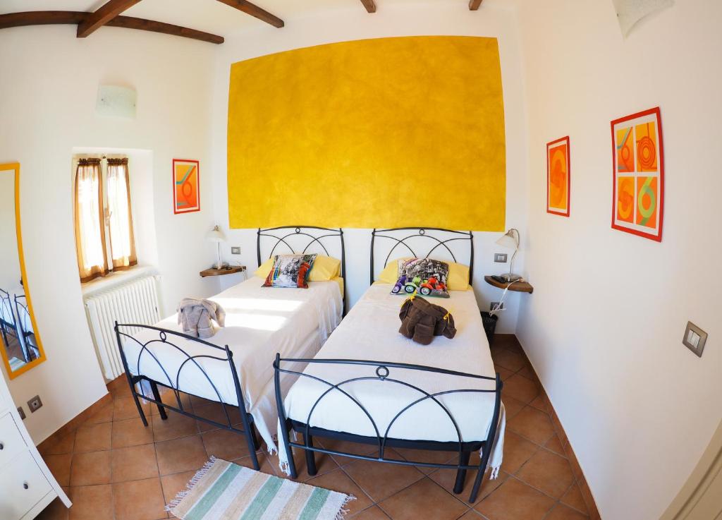 Pietra Di Mare في Biassa: غرفة نوم بسريرين وجدار اصفر