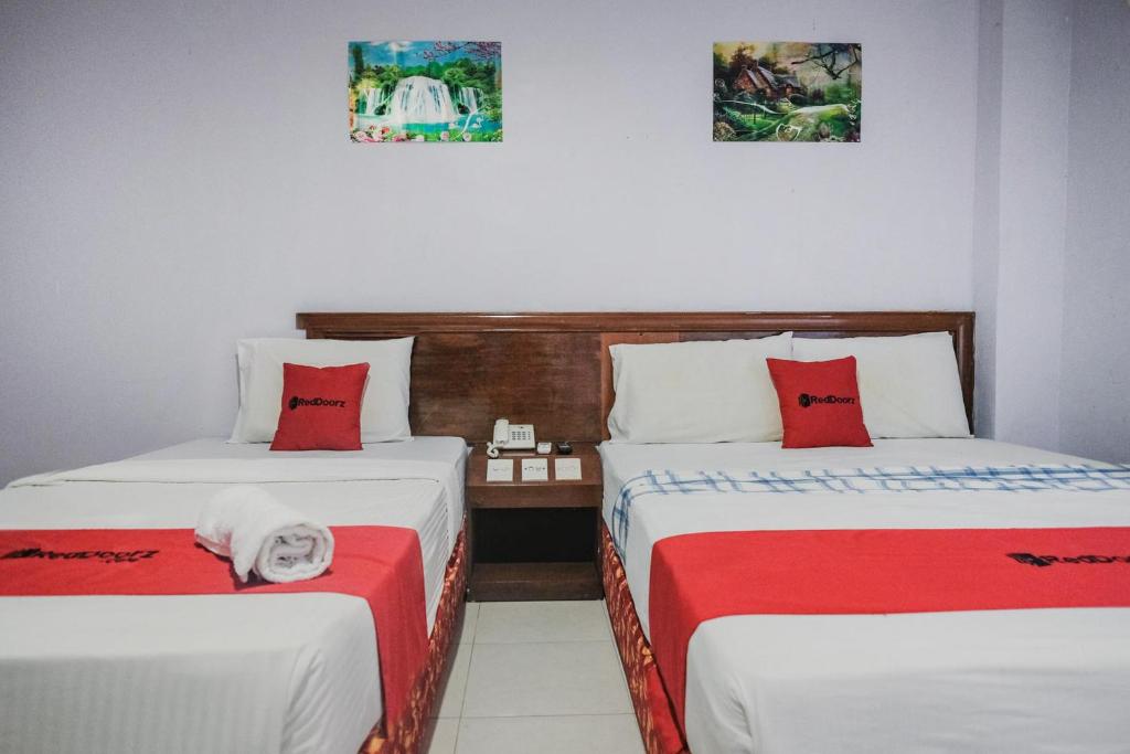 a room with two beds with red and white sheets at Reddoorz near Nagoya Hill Mall Batam 5 in Batam Center