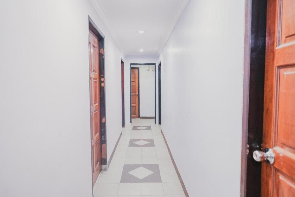 a hallway with white tile floors and a brown door at Reddoorz near Nagoya Hill Mall Batam 5 in Batam Center