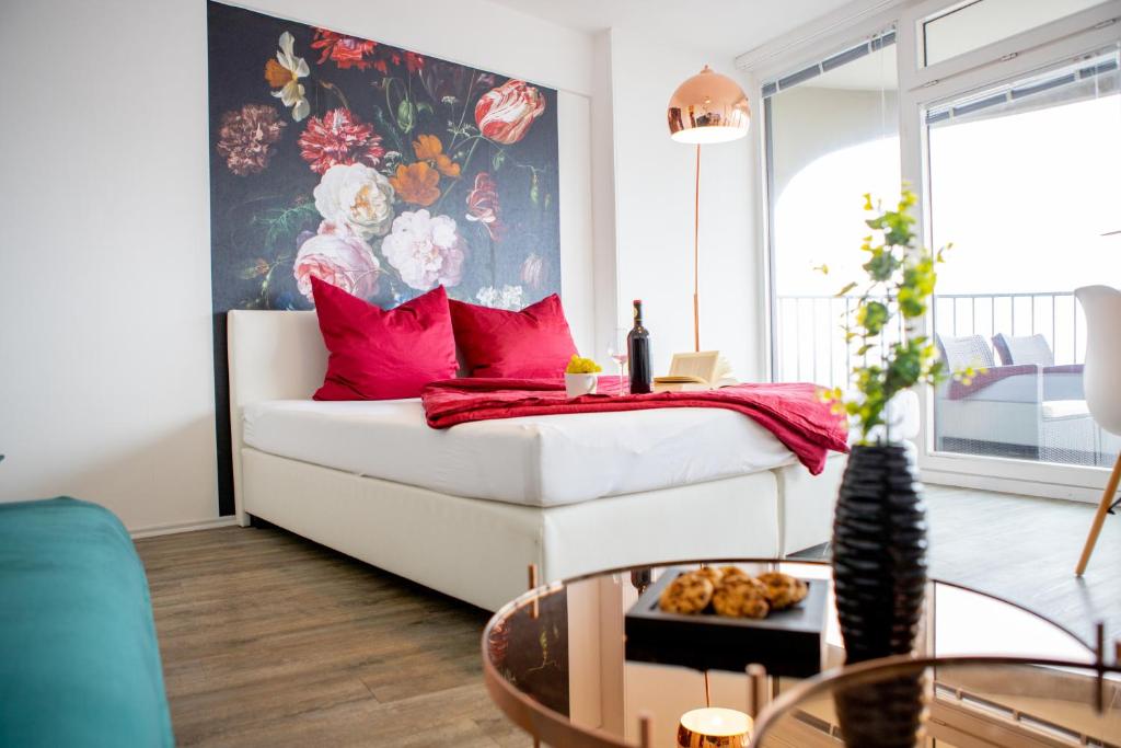 een woonkamer met een witte bank en rode kussens bij Modernes Apartment mit tollem Blick über die Stadt in Augsburg