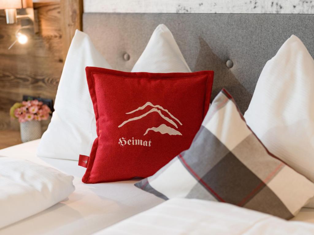 a red pillow on a bed with white pillows at Echt Woods Appartements in Söll