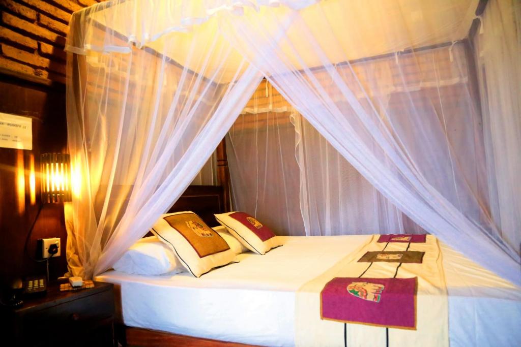 a bedroom with a canopy bed with white curtains at D Family Resort in Anuradhapura