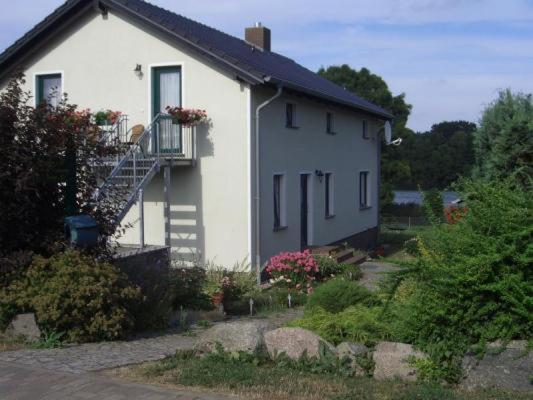 a white house with a porch and a balcony at Seeidyll in Zemitz
