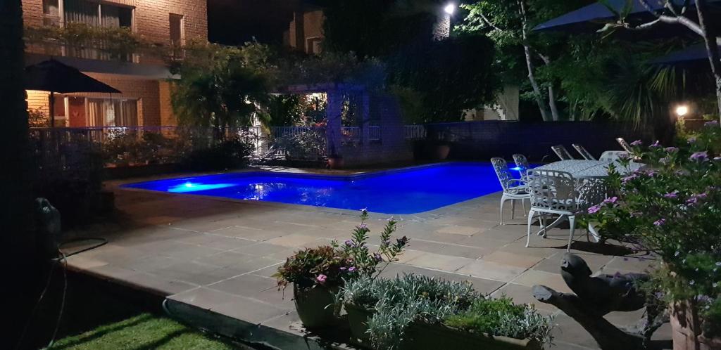 una piscina con mesa y sillas en un patio trasero por la noche en Whittlers Lodge, en Hout Bay