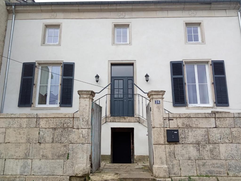 een wit huis met een zwarte deur en een stenen muur bij la maison de Valbois in Varvinay