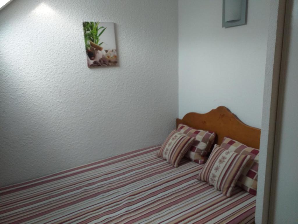 a bed with two pillows and a picture on the wall at Appartement F2 au domaine des 100 lacs - piscine - sauna - hammam in Cauterets