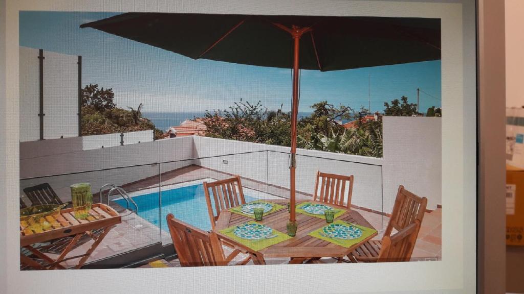 - une table avec un parasol à côté de la piscine dans l'établissement Casa Branca, à Funchal