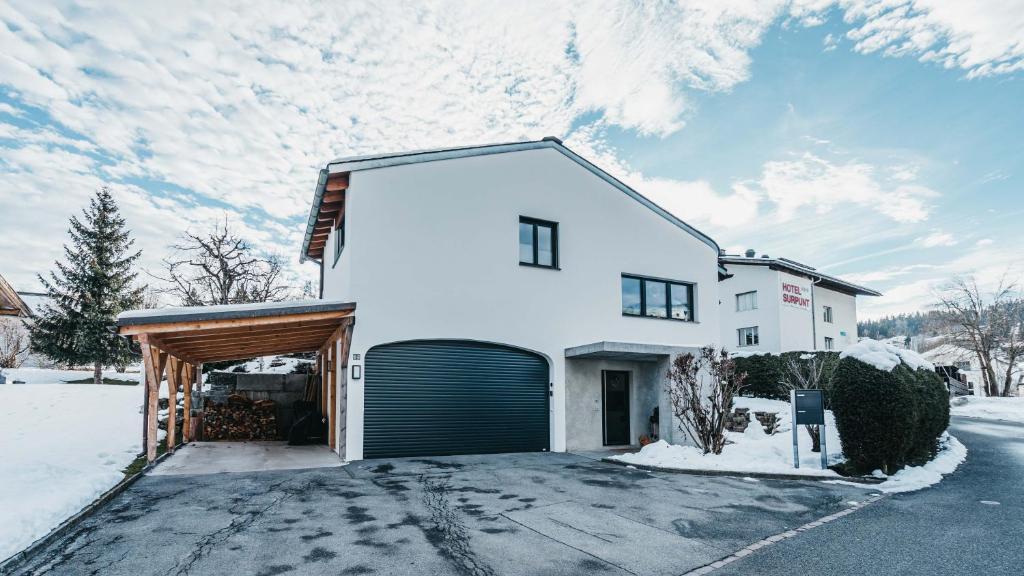una casa blanca con un garaje en la nieve en Charming 4 bed flat in Flims, en Flims