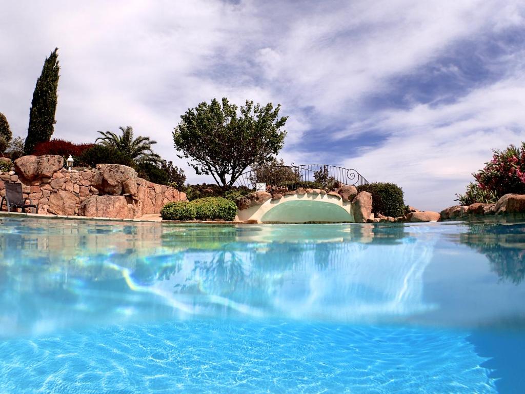 a large pool of blue water with a bridge at Résidence Liccia di Furu in Porto-Vecchio