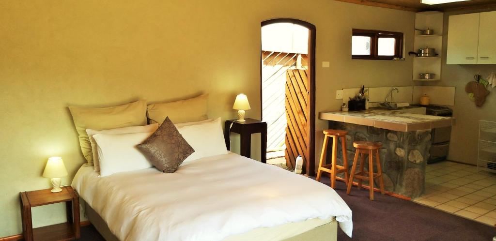 a bedroom with a white bed and a kitchen at Masalimo Cottage in Rhodes