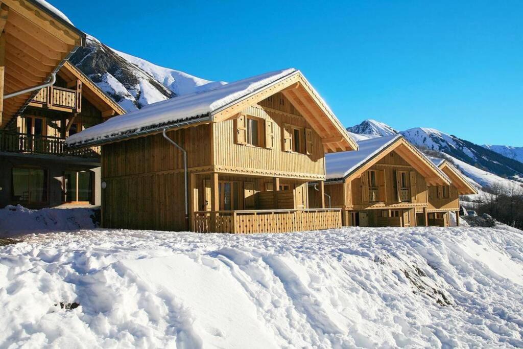 ein Holzhaus im Schnee mit Bergen im Hintergrund in der Unterkunft Chalet cosy Duplex 6 personnes in Saint-Sorlin-dʼArves