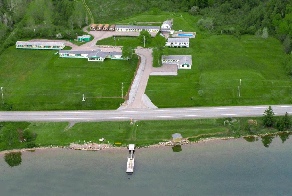 an aerial view of a school with a road and water at Cabot Trail Motel in Baddeck