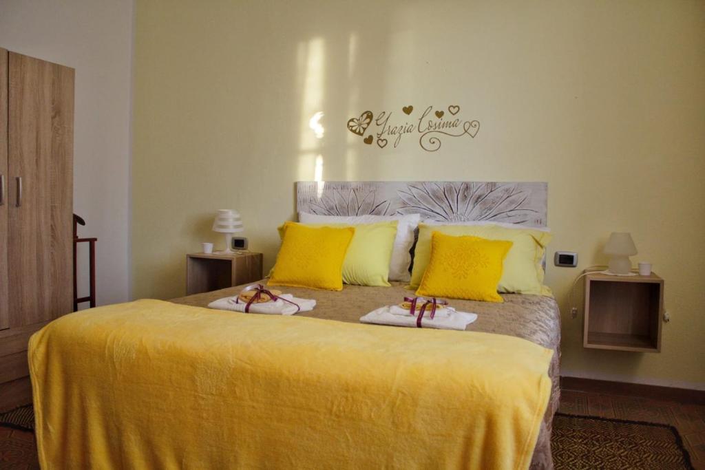 a bedroom with a bed with yellow sheets and slippers at La Collina dei Ciliegi in Sarule