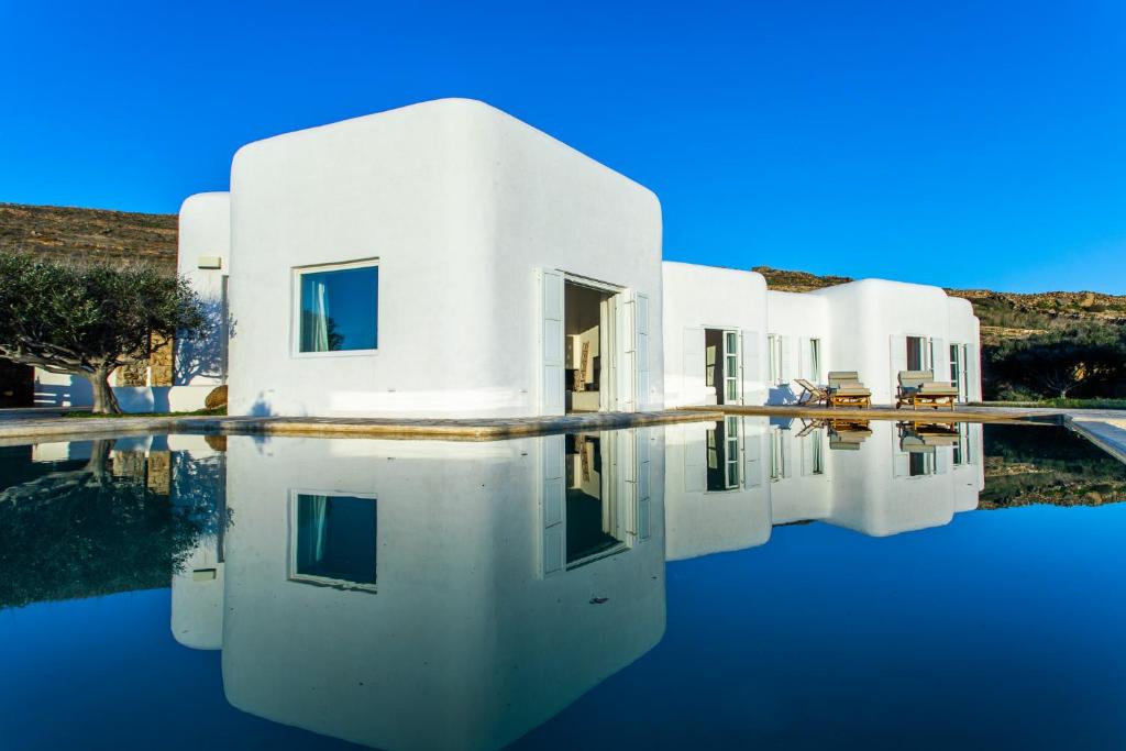 a white house with its reflection in the water at Zen Residence in Lia beach in Kalafatis