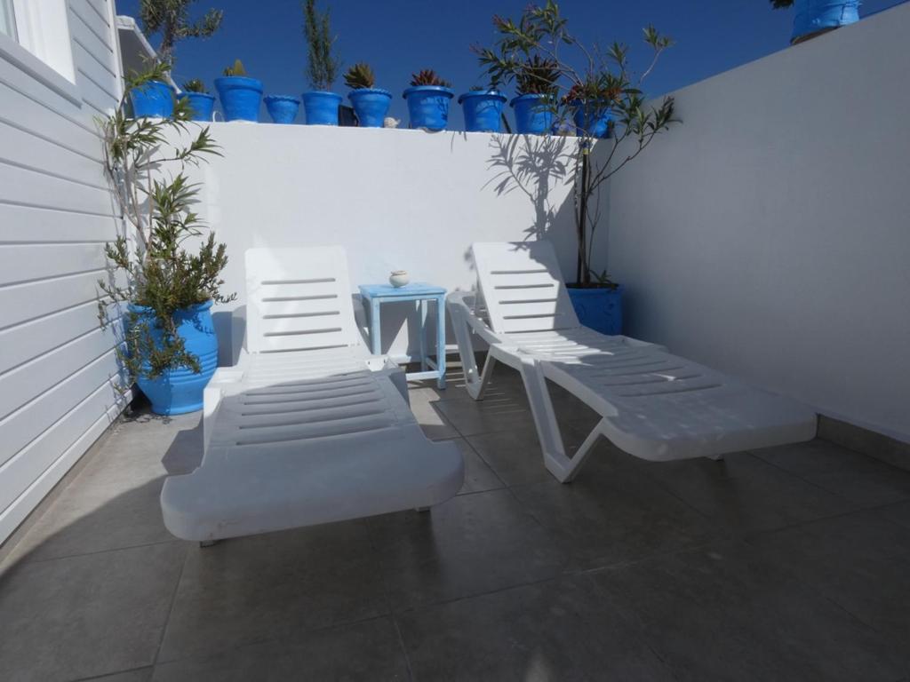 3 weiße Sessel, ein Tisch und Topfpflanzen in der Unterkunft Chez Khadija Et Franz in Essaouira