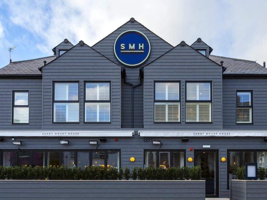 a building with a blue sign on the front of it at Sandy Mount House in Rhosneigr