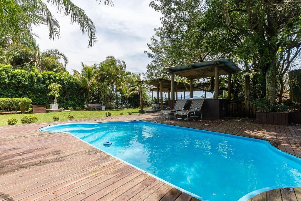 una piscina azul en un patio con terraza de madera en Apto pé na areia em Jurerê JBM201, en Florianópolis