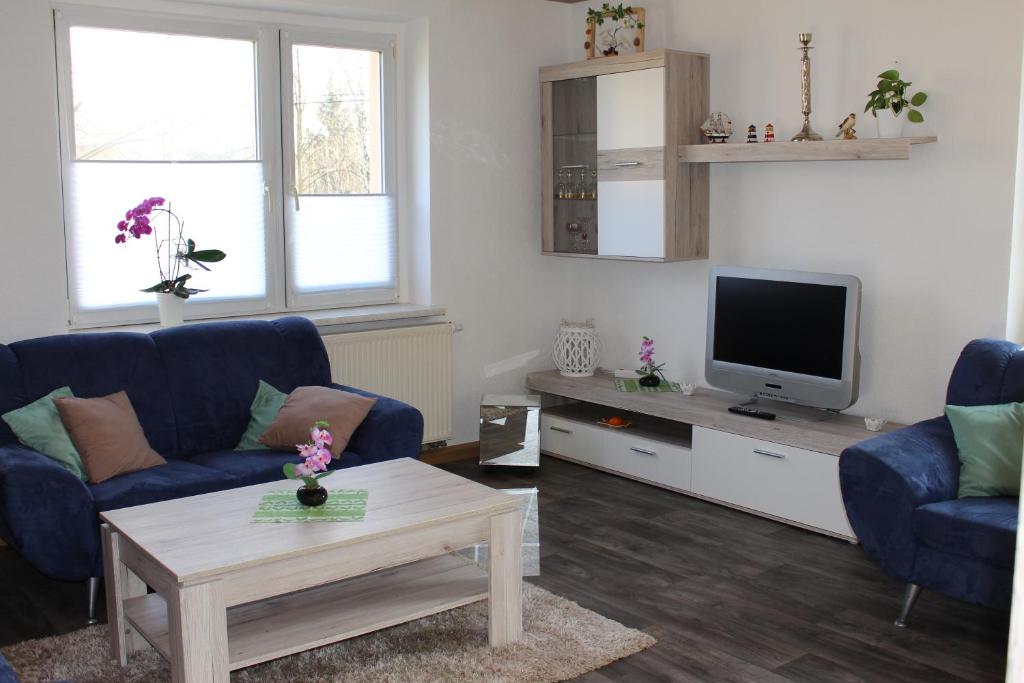 a living room with two blue chairs and a tv at Ferienwohnung Beim Rößl in Nossen