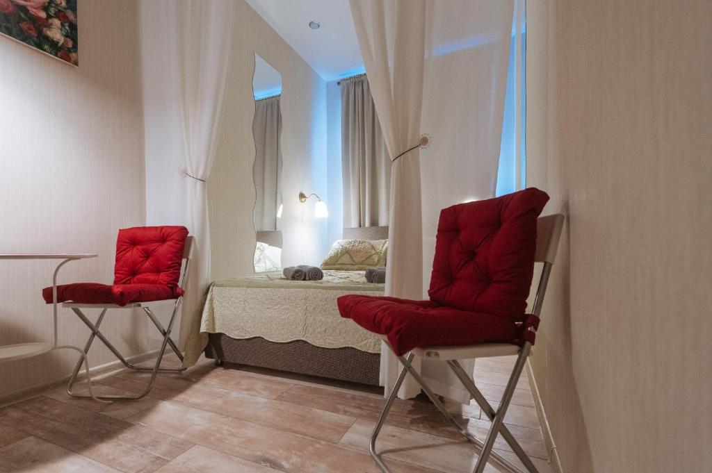 モスクワにあるApart-Hotel Belomorskayaの赤い椅子2脚とベッド1台が備わる客室です。