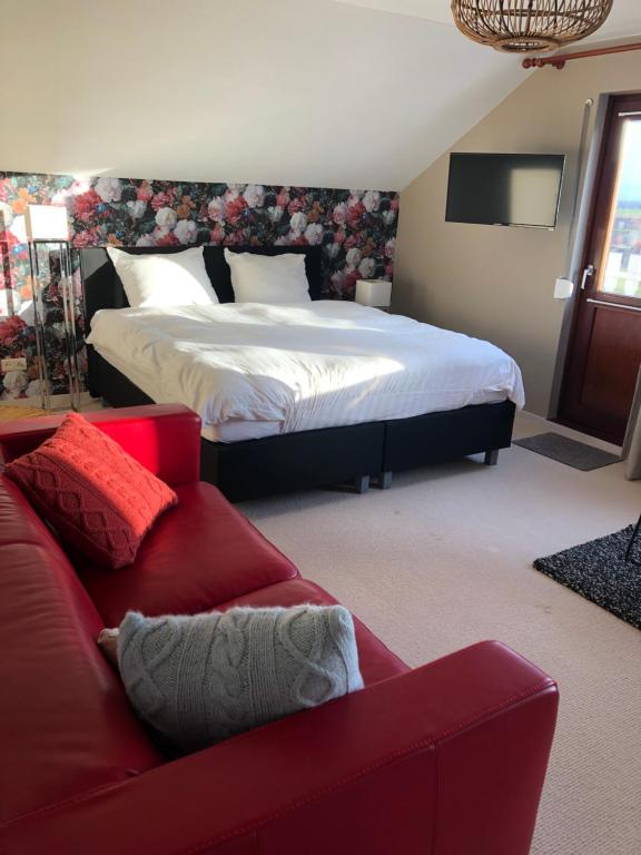 een slaapkamer met een bed en een rode bank bij De grote Zeearend in Aardenburg