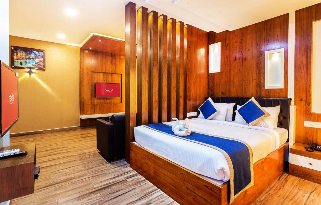 1 dormitorio con 1 cama y TV en una habitación en Nextel Inn, Calicut en Kozhikode