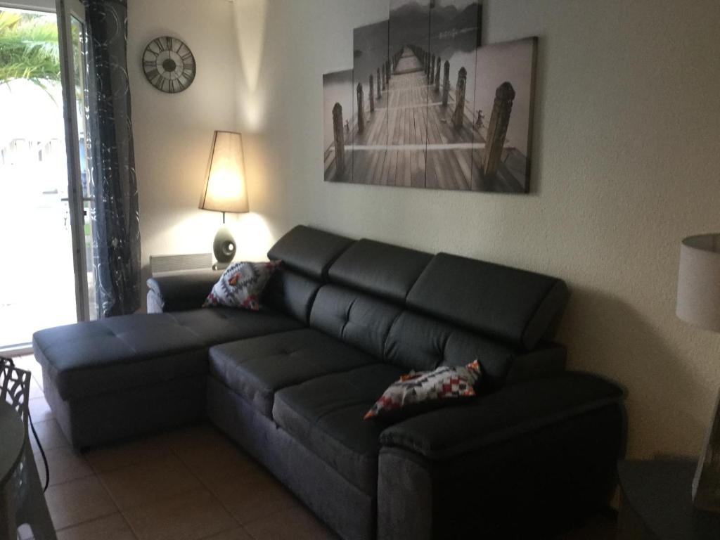 ein Wohnzimmer mit einem schwarzen Sofa und einem Tisch in der Unterkunft ANGLET- BIARRITZ T3 dans résidence avec piscine in Anglet