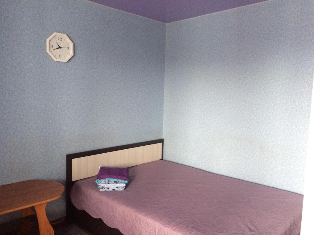 a small bedroom with a bed and a clock on the wall at Квартира 40 лет Победы,12 in Bratsk