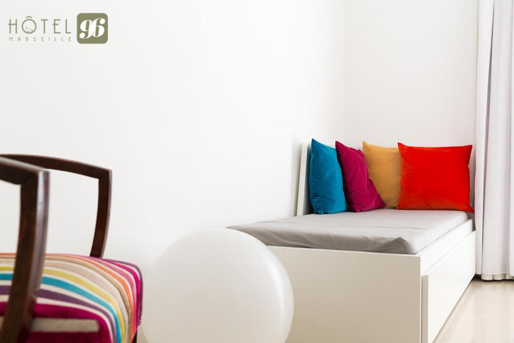 a room with a couch with colorful pillows on it at Hôtel 96 in Marseille