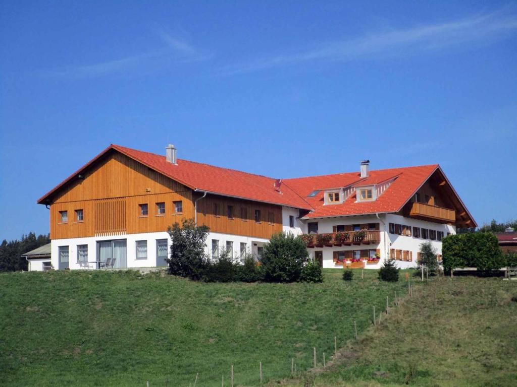 un grand bâtiment avec un toit rouge sur une colline dans l'établissement Ferienbauernhof Köpf, à Füssen