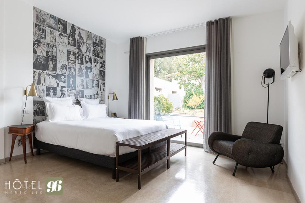 a bedroom with a bed and a chair and a window at Hôtel 96 in Marseille