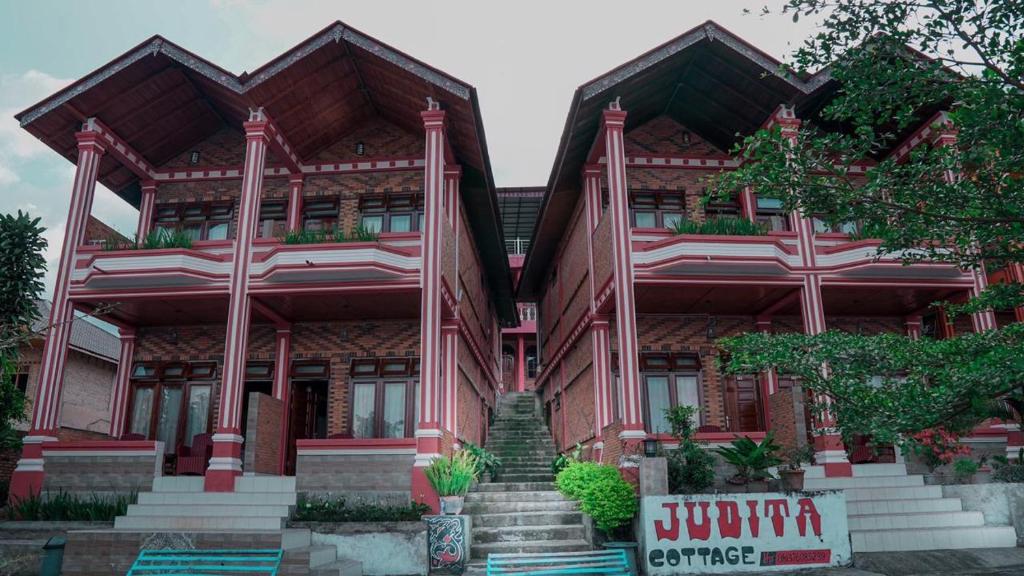 a red building with stairs in front of it at Judita Cottage in Tuktuk Siadong