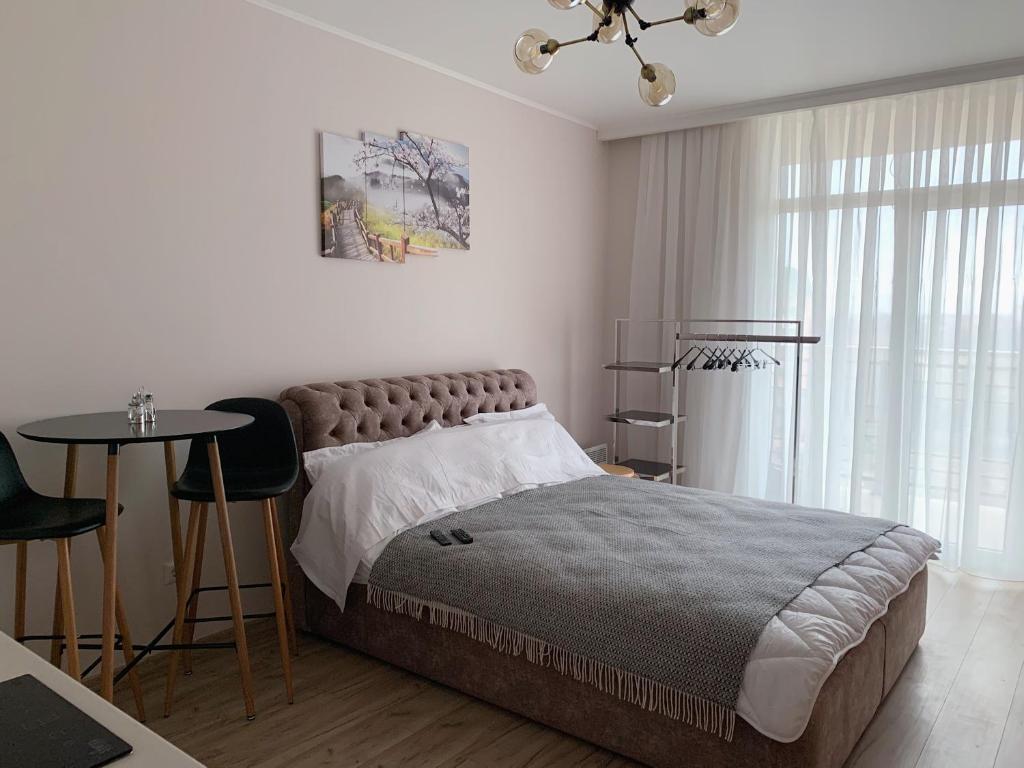 a bedroom with a large bed with a table and a chair at Апартаменти-студія на Герцена in Chernivtsi