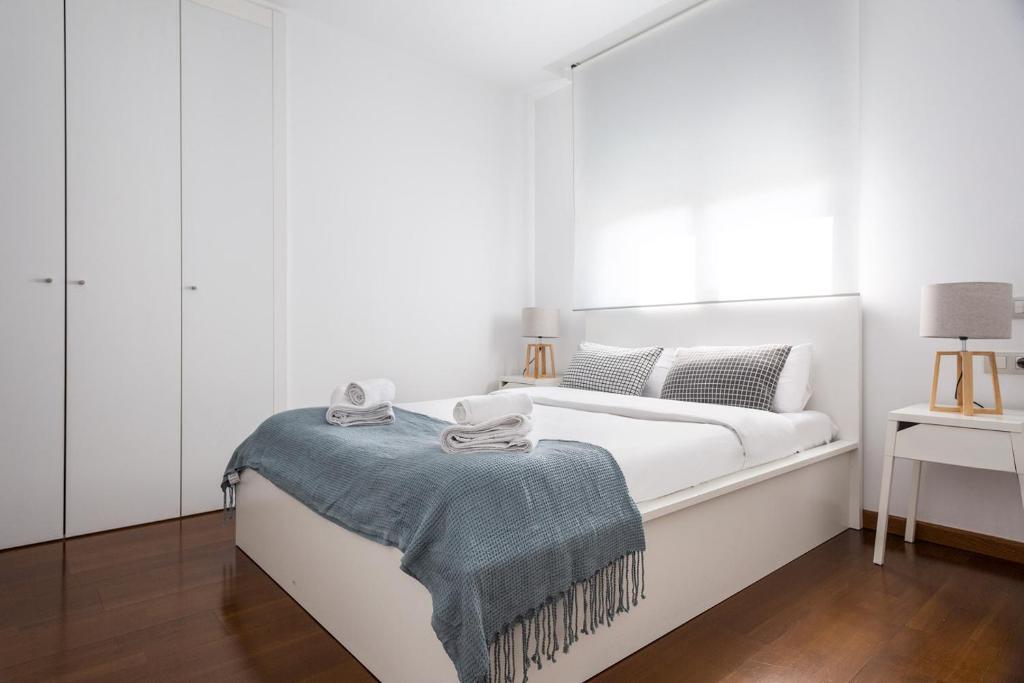 Un dormitorio blanco con una cama con una manta azul. en Les Corts Exclusive Apartments by Olala Homes, en Barcelona